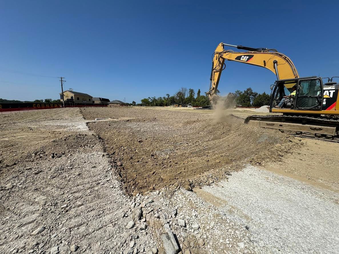 A large yellow excavator is working on a dirt field.