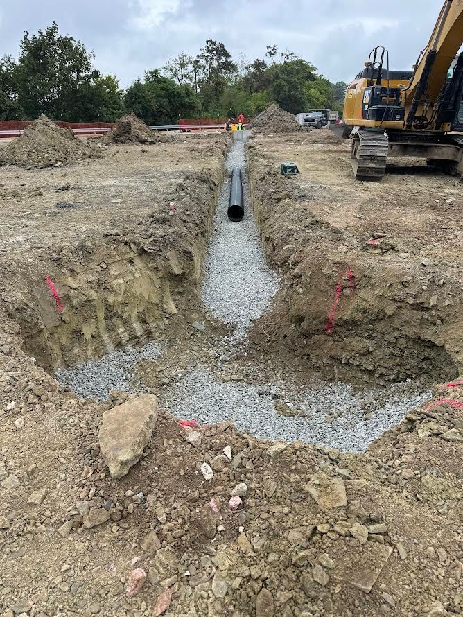 A large excavator is digging a trench in the dirt.