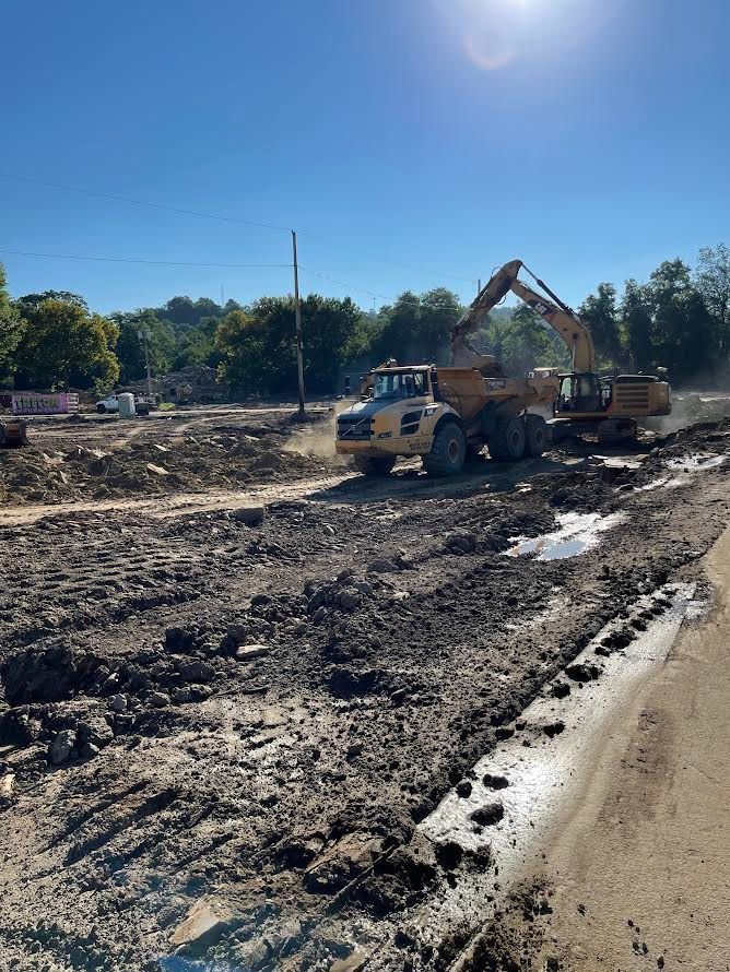 A large yellow dump truck is driving down a muddy road.