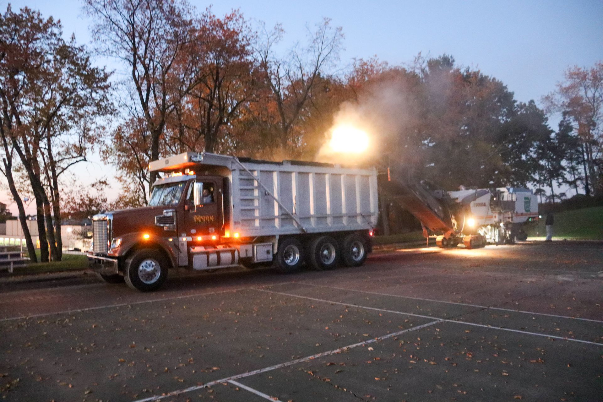 A dump truck is parked in a parking lot at night