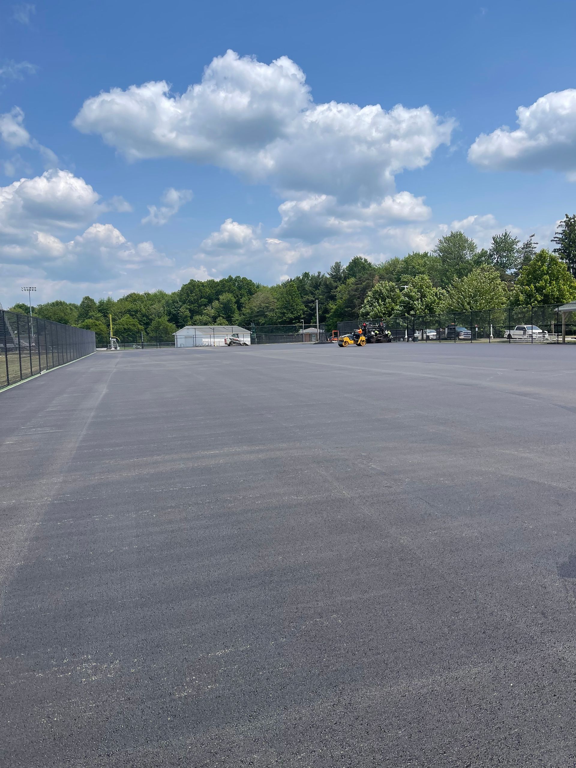 A large empty parking lot with trees in the background