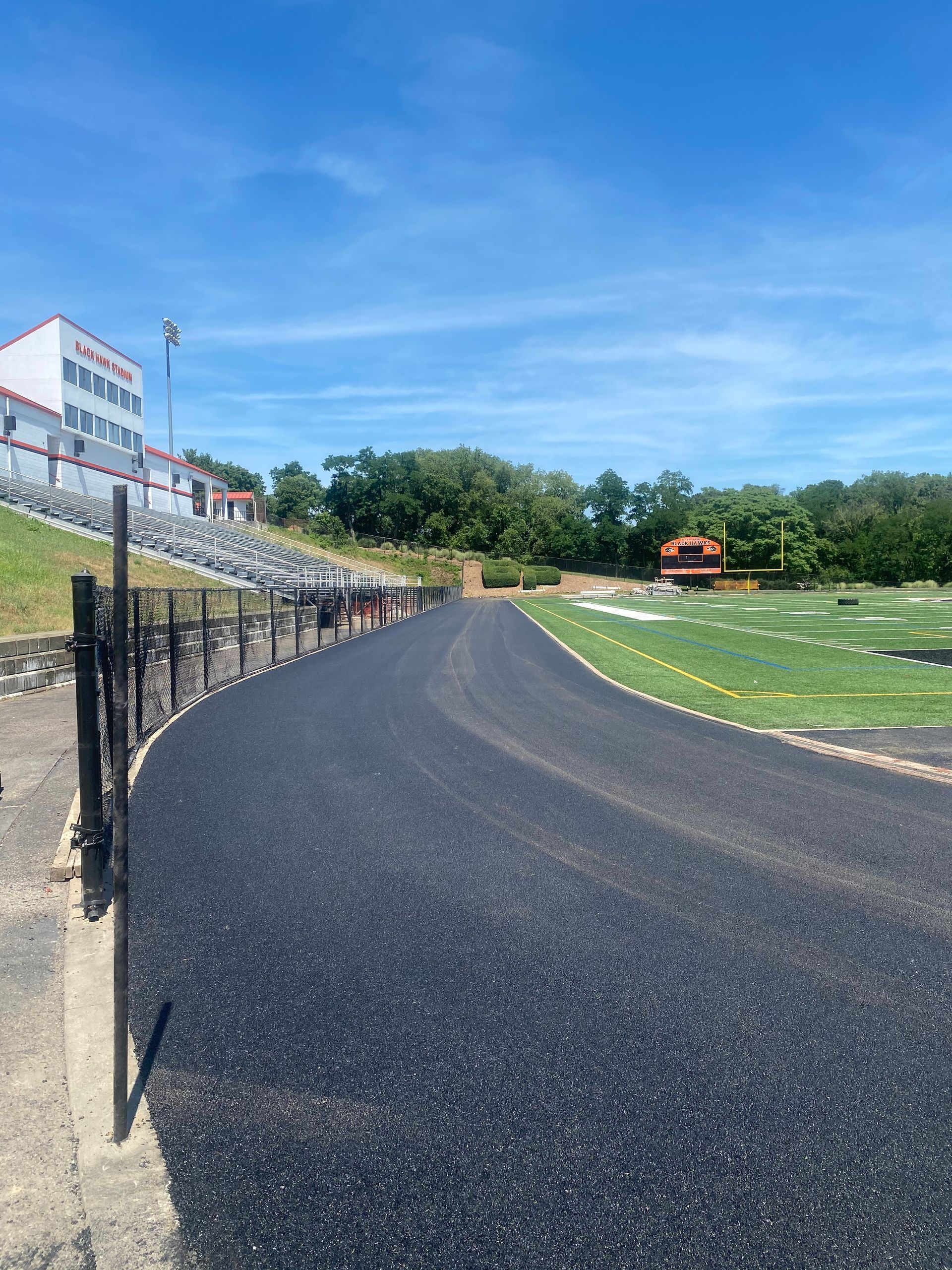 A track with a fence around it and a building in the background.