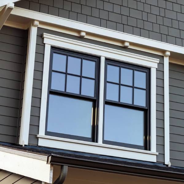 A window on the side of a house with a white trim