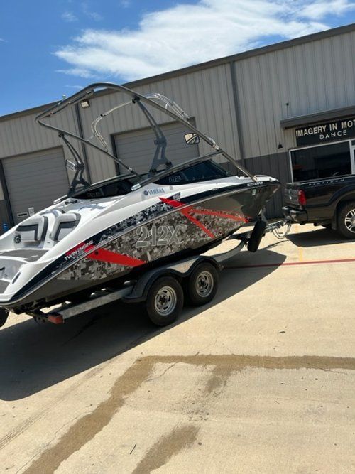 A boat is being towed by a truck in front of a building.