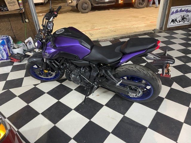 A purple motorcycle is parked on a checkered floor in a garage.