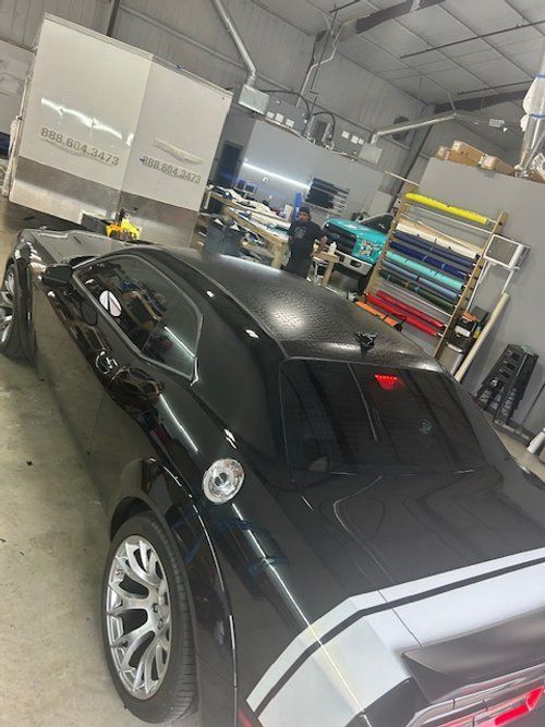A black dodge challenger is parked in a garage.