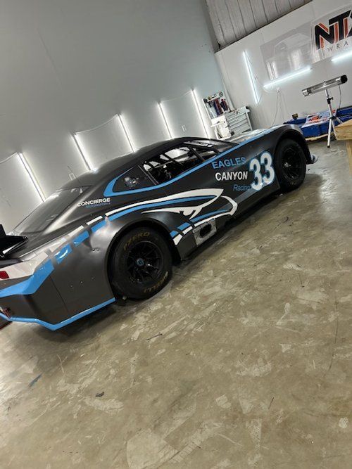 A race car with the number 33 on the side is parked in a garage.