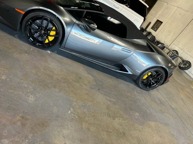 A gray sports car with yellow brake calipers is parked in a garage