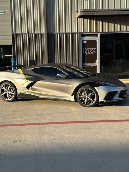 A silver sports car is parked in front of a building.