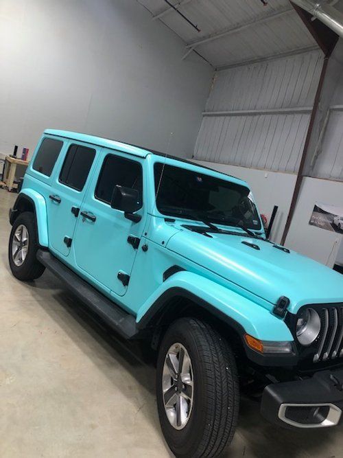 A blue jeep is parked in a garage.