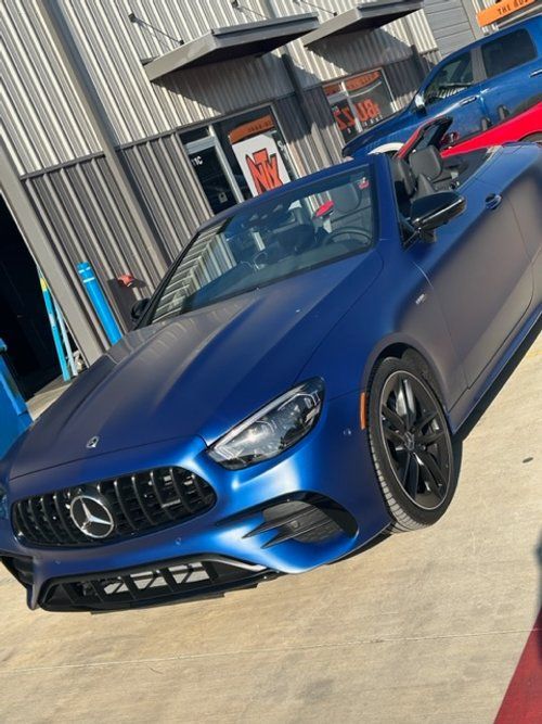 A blue mercedes is parked in front of a building