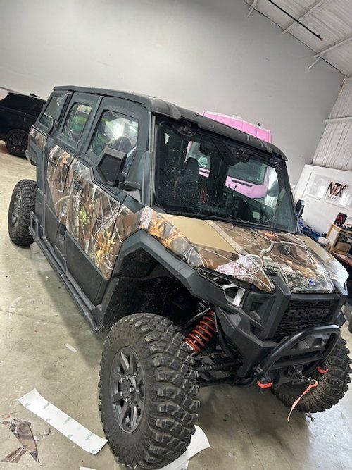 A camouflage covered atv is parked in a garage.