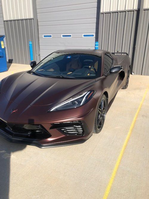 A purple sports car is parked in a parking lot in front of a building.
