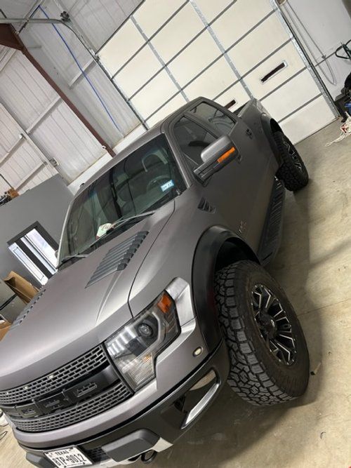 A ford raptor truck is parked in a garage.