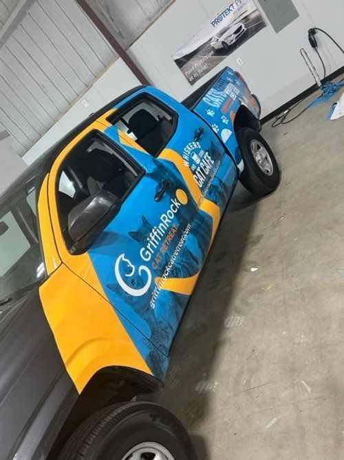 A blue and yellow truck with griffin rock written on the side