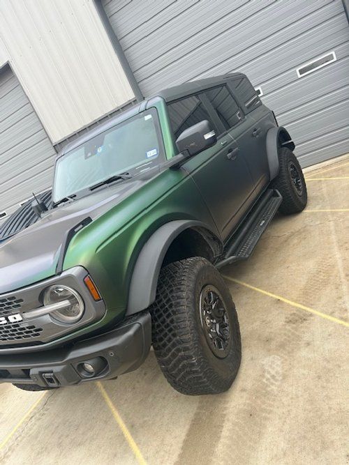 A black and green ford bronco is parked in a parking lot.