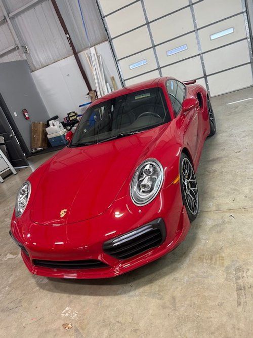 A red porsche 911 turbo s is parked in a garage.