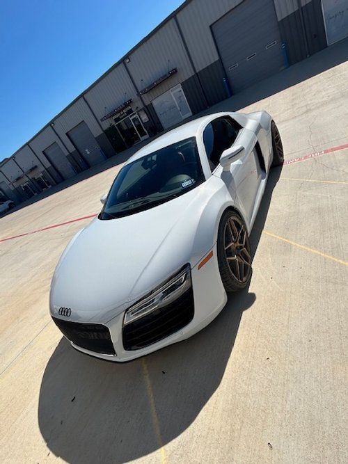 A white audi r8 is parked in a parking lot