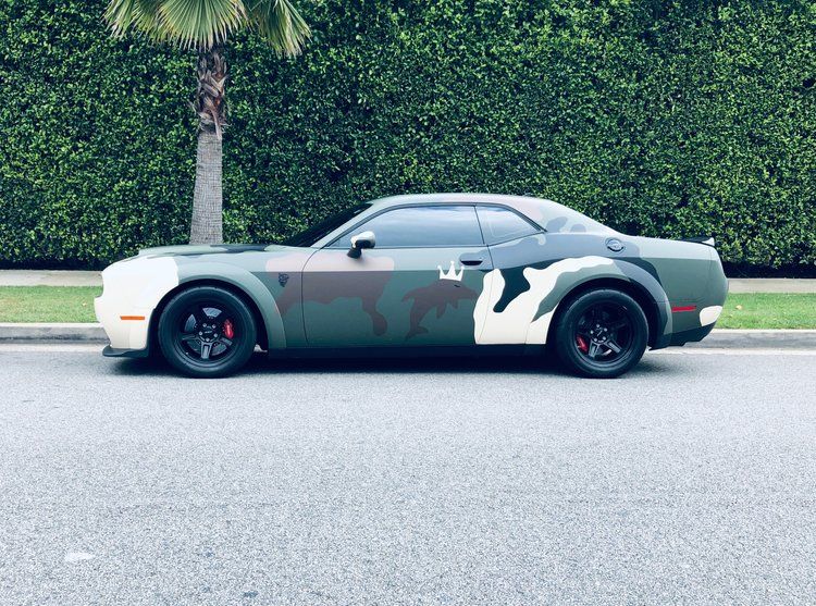 A green and white dodge challenger is parked on the side of the road.
