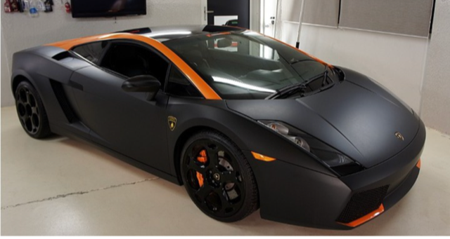 A black and orange sports car is parked in a garage