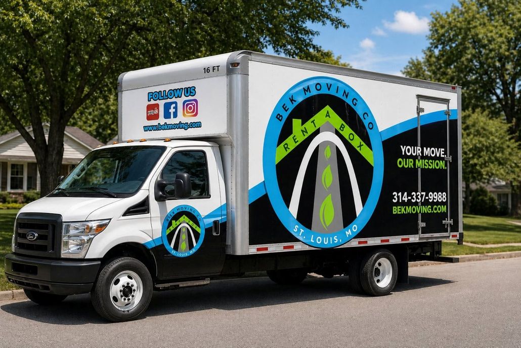 White moving truck with blue and green logo parked on a suburban street with trees and houses.