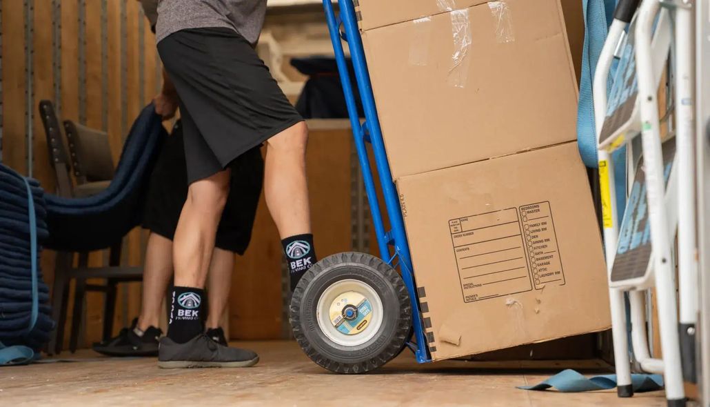 Person sealing a cardboard box with packing tape in a bright office workspace