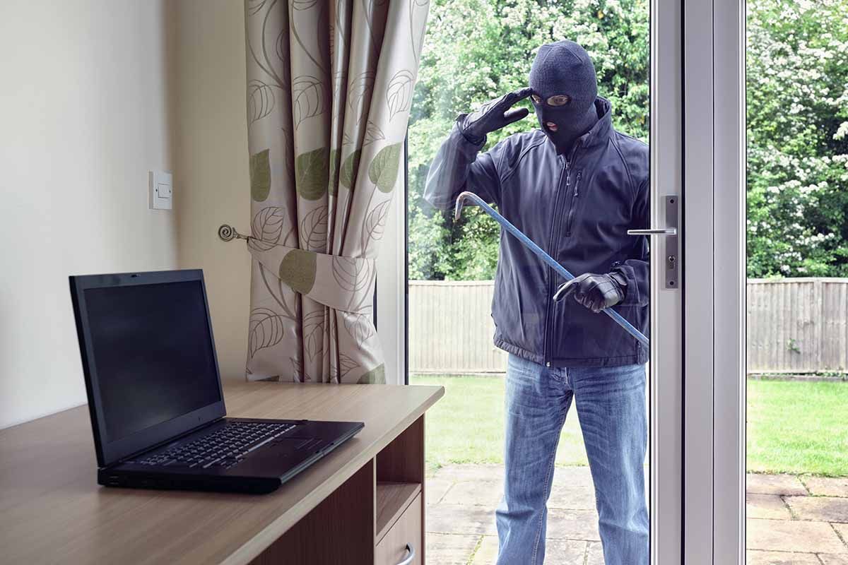 a man in a mask is breaking into a house with a laptop on a desk