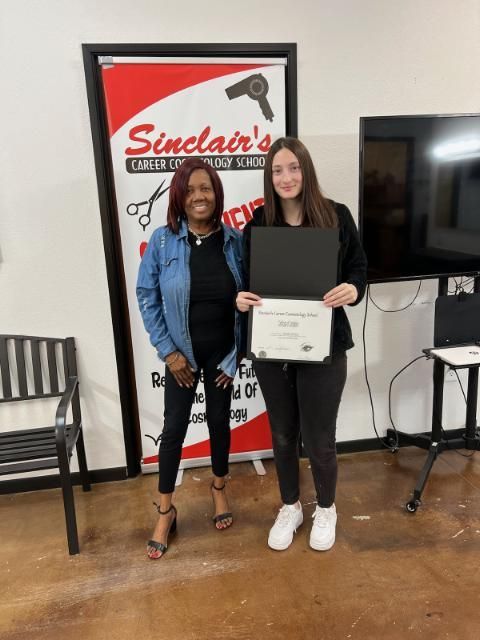 Two women standing next to each other in front of a sinclair 's sign