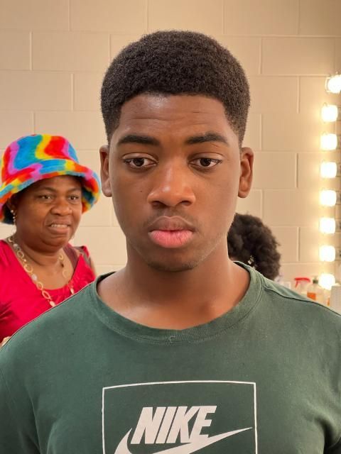 A young man wearing a green nike shirt looks at the camera