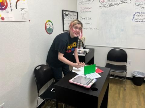 A woman is standing in front of a desk with a tablet on it.