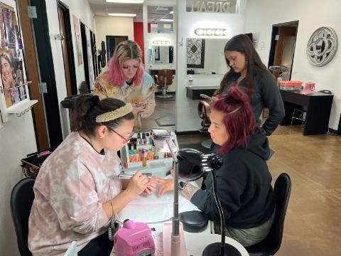 A group of women are sitting at a table in a salon getting their nails done.
