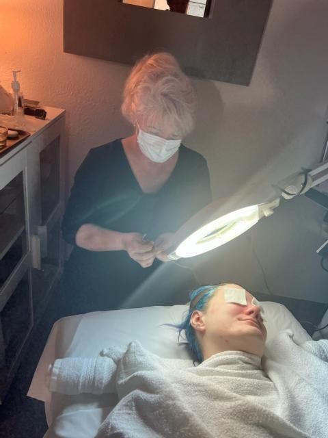 A woman wearing a mask is looking at a woman laying on a bed