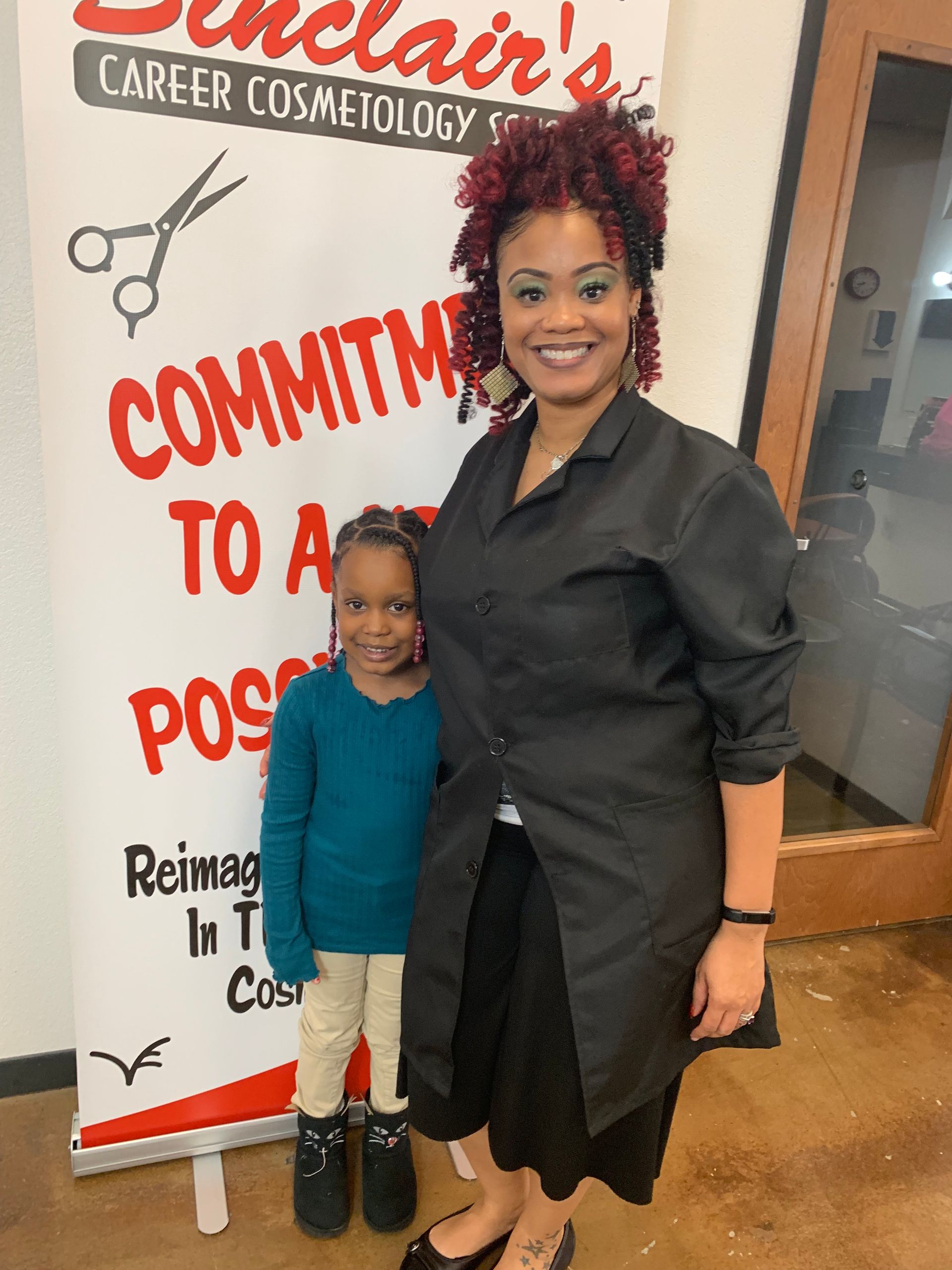 A woman and a little girl are standing in front of a sign that says commit to a position