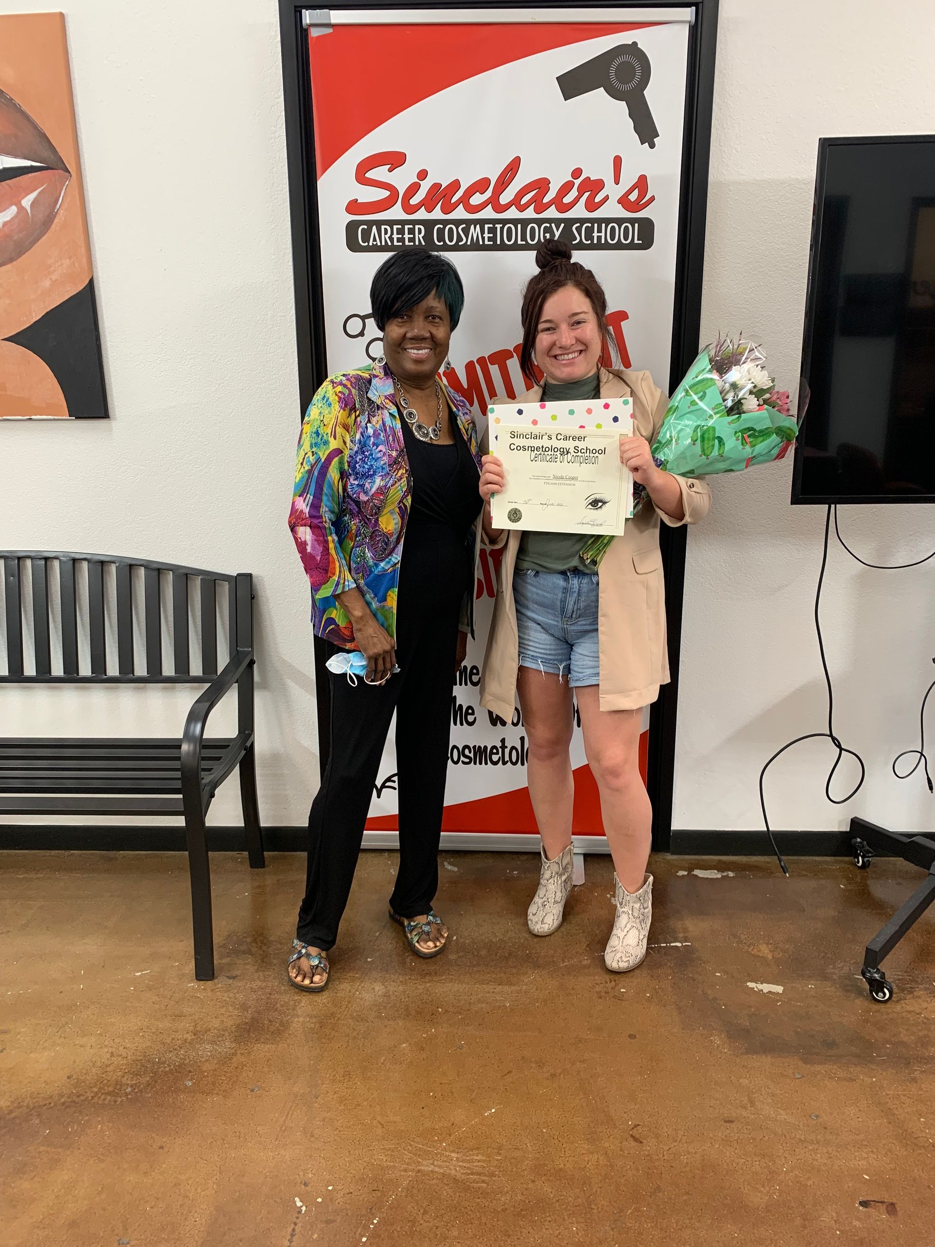 Two women are standing next to each other in front of a sinclair 's sign.