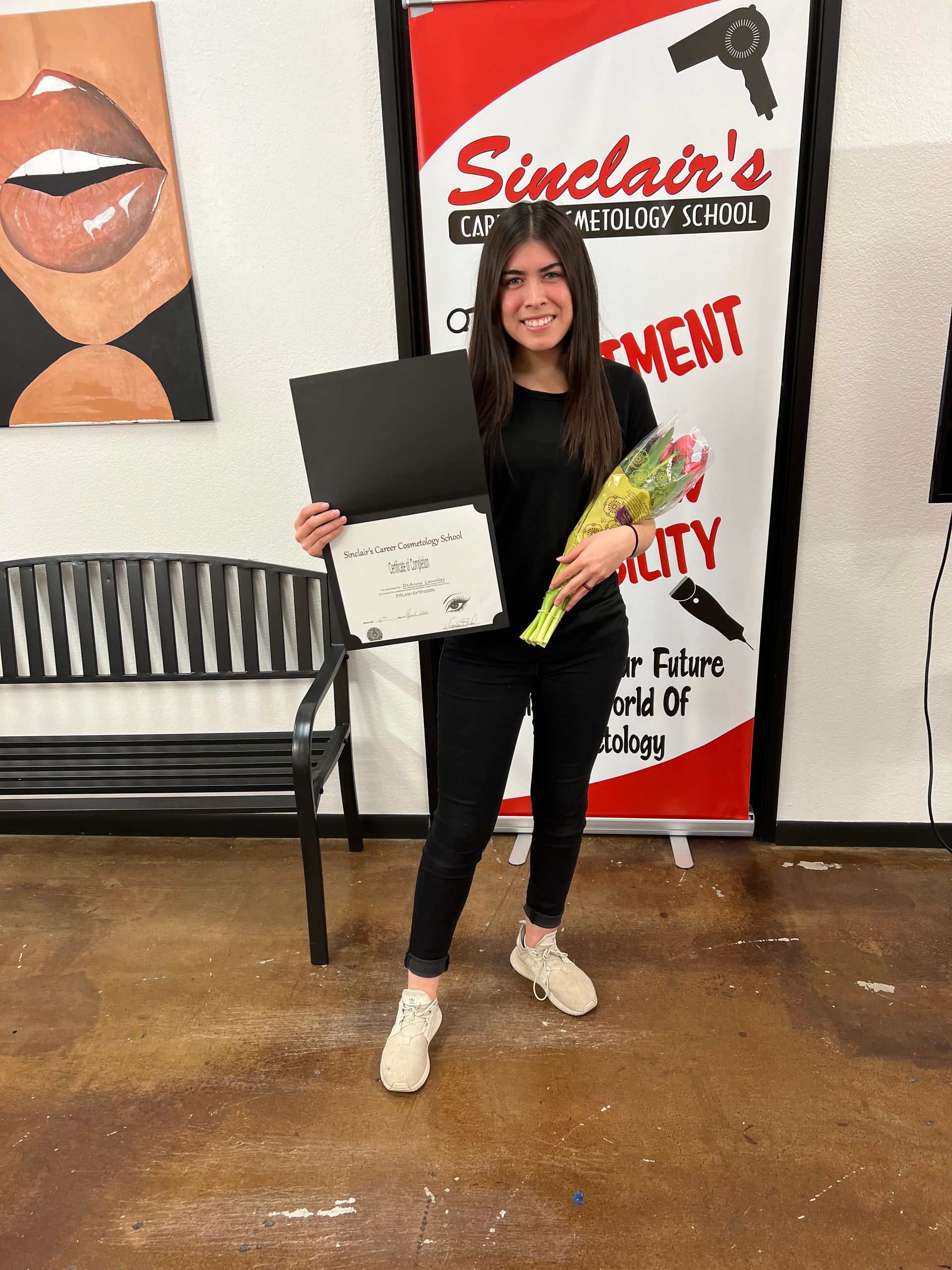 A woman is holding a bouquet of flowers and a certificate.