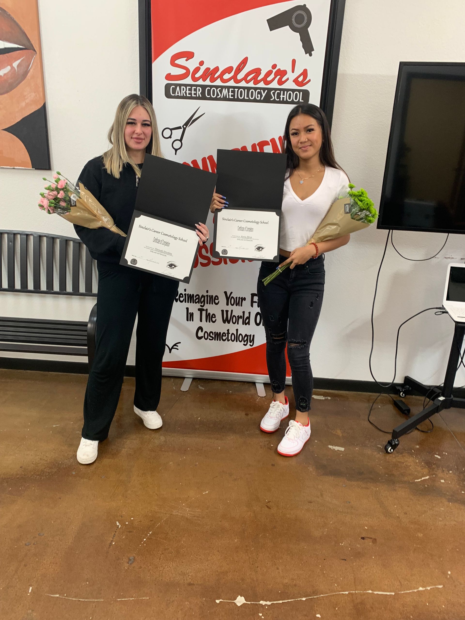 Two women are standing next to each other in front of a sign that says sinclair 's