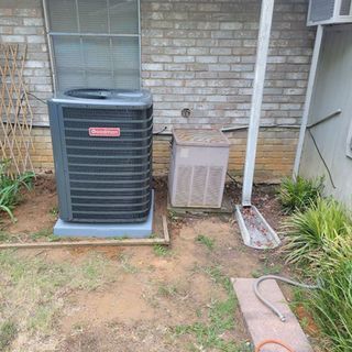 An air conditioner is sitting on the side of a brick building.