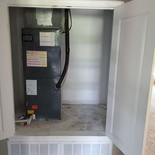 An air conditioner is sitting inside of a closet.