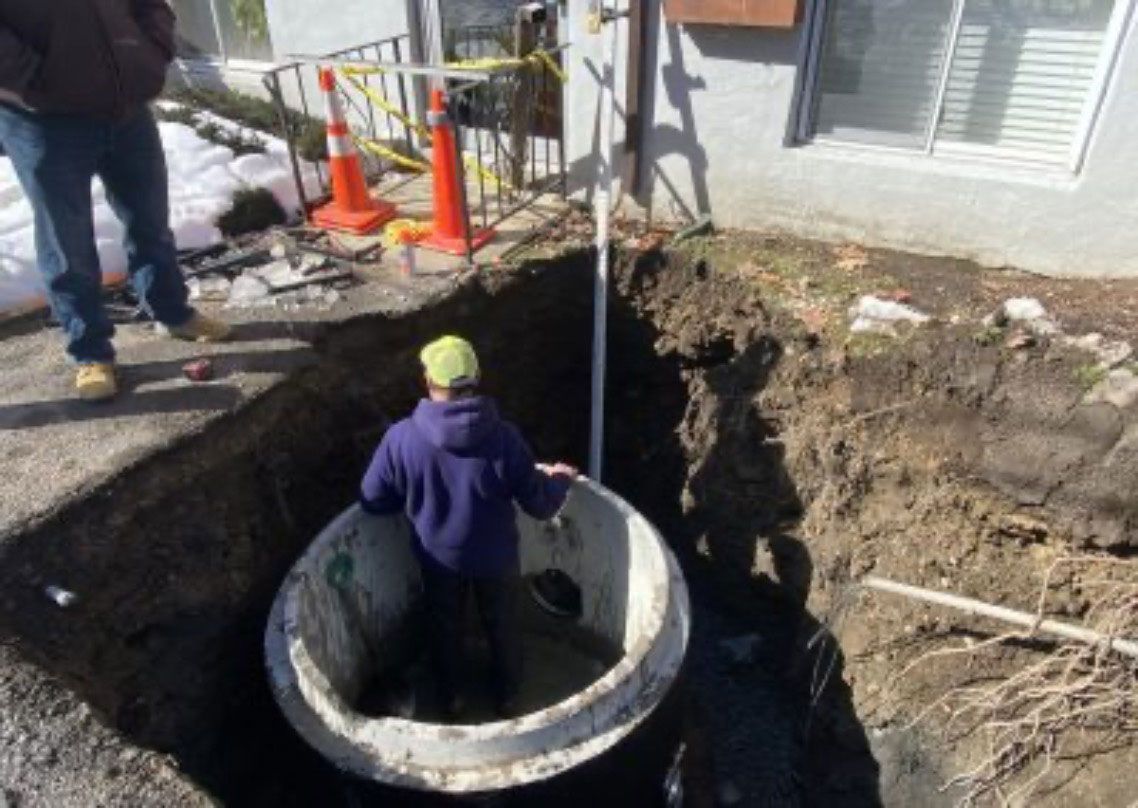 Worker standing in a large underground utility pit at a construction site