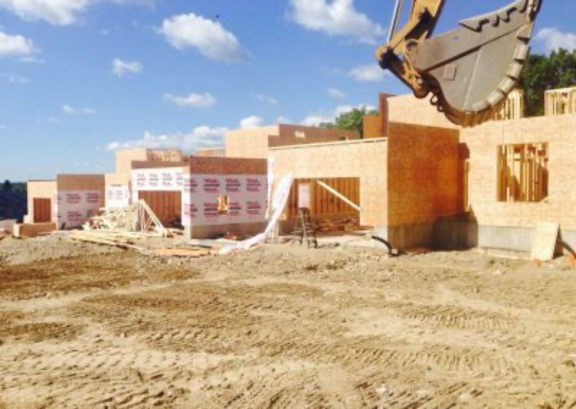 Construction site with a bulldozer, partially built brick buildings, and sandy ground under a blue sky