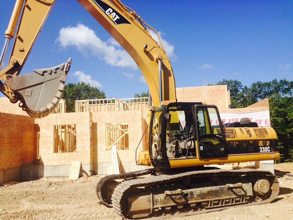 Yellow excavator working at a building construction site under a clear blue sky