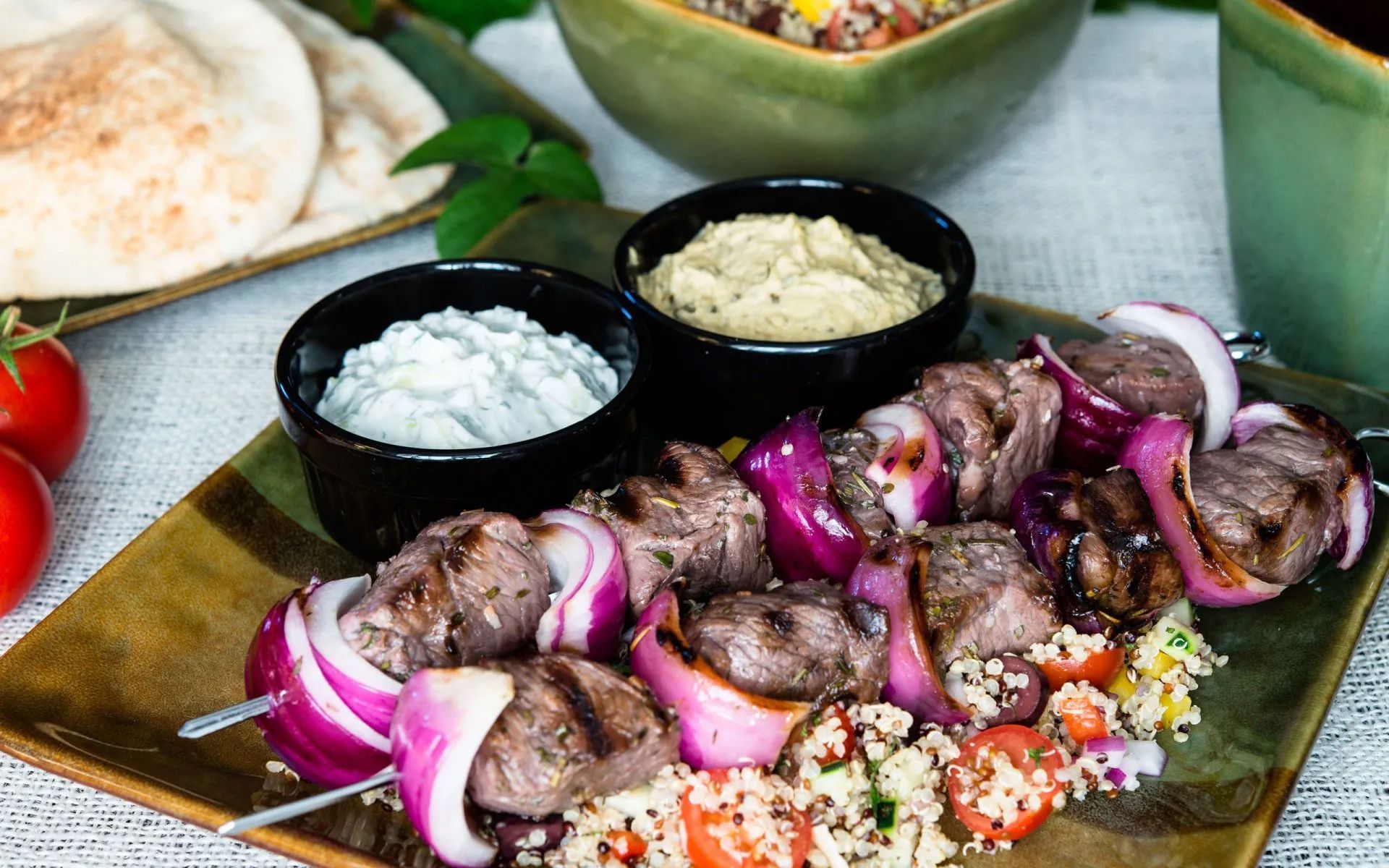 a plate of food with meat, onions, tomatoes and dips on a table