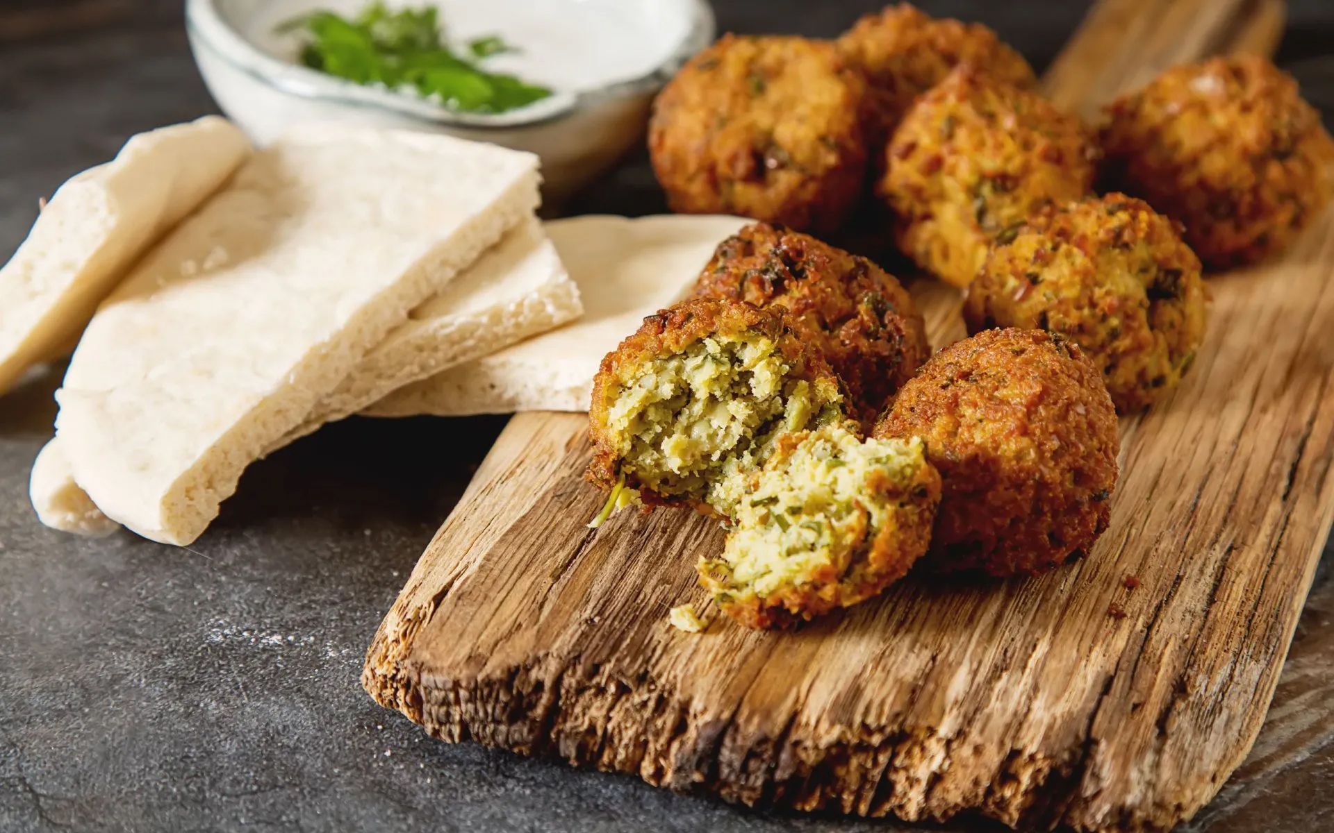 a wooden cutting board topped with falafel and pita bread
