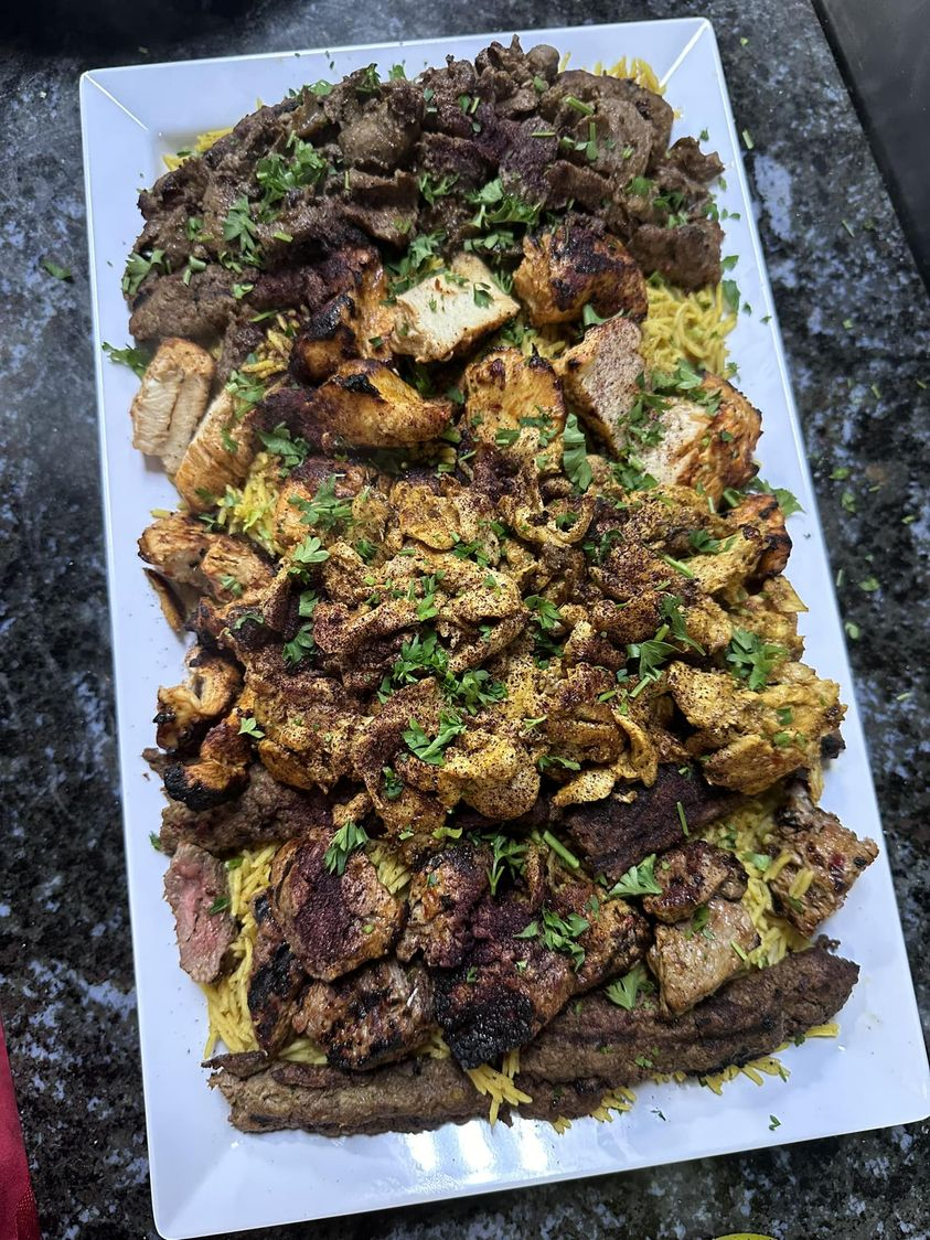 a white plate topped with a variety of meats and rice on a table .