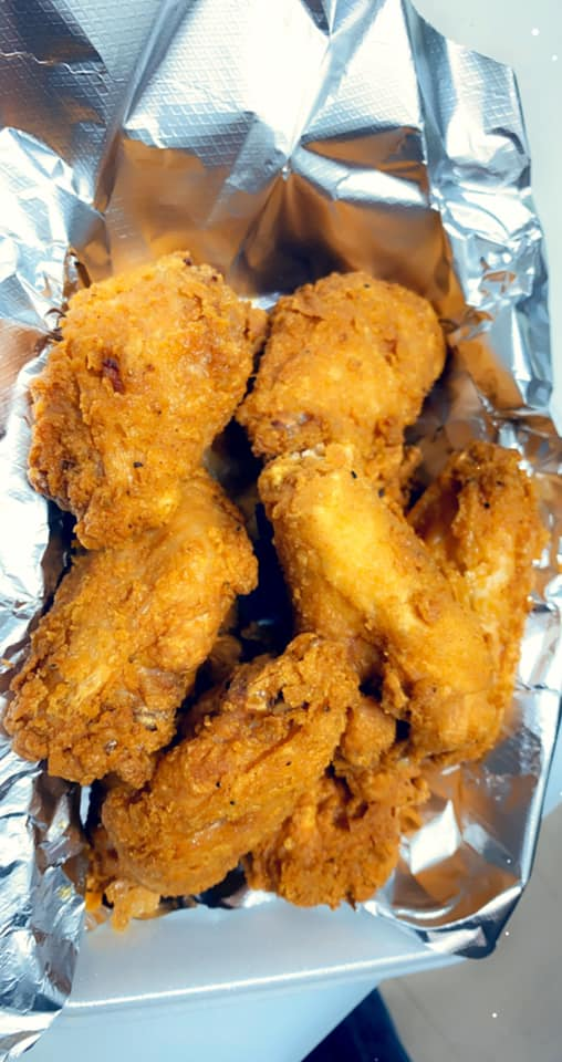 a close-up of fried chicken wings wrapped in tin foil