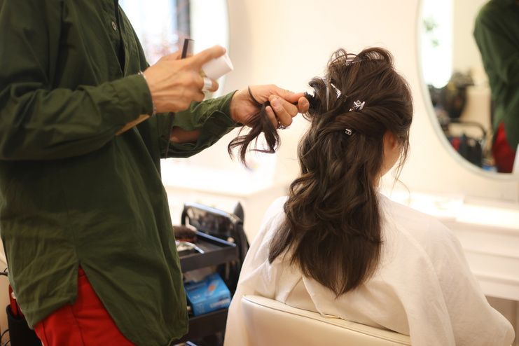 Hair stylist spraying hair of a person seated in a salon chair.