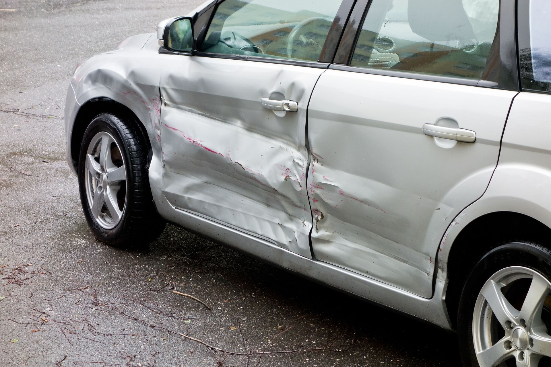 Silver car with severe damage to the driver's side doors.