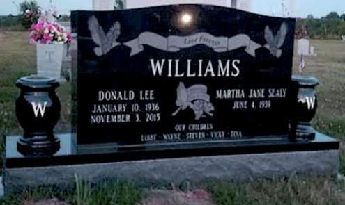 A black granite double headstone for the Williams family with engraved names, dates, and dove motifs in a cemetery.