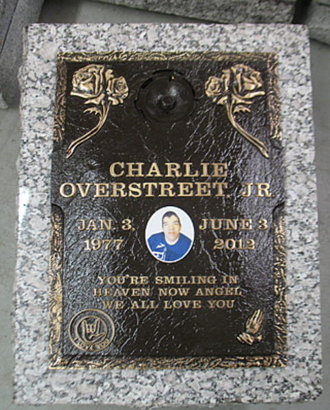 A bronze memorial plaque on a granite base for Charlie Overstreet Jr. (1977-2012) featuring his photo and an inscription.