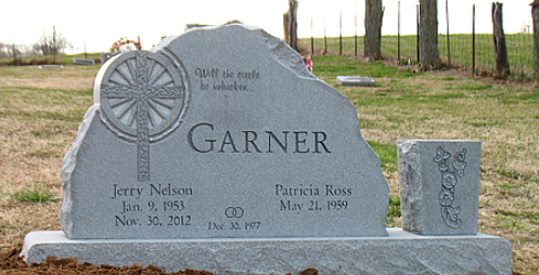 A gray granite double headstone for the Garner family, featuring a cross engraving, names, and dates, in a cemetery.